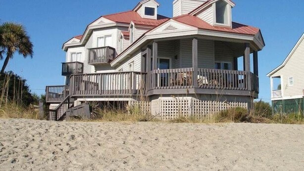 A beachfront house with a balcony, a covered porch, and a staircase leading to the entrance. - The Point (Edisto Island)