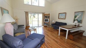 A spacious living room with a sofa, a coffee table, and a TV stand. - Creamsicle (Edisto Island)