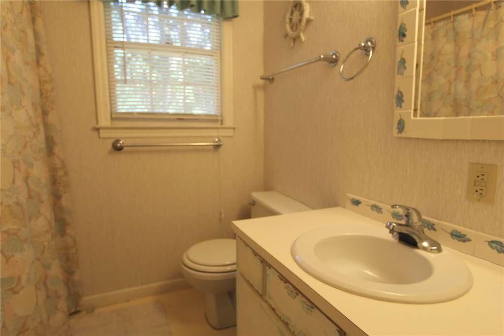 A bathroom with a toilet, sink, and window.