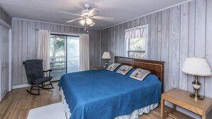 A bedroom with a large bed, a rocking chair, a wooden floor, and a ceiling fan. - Crowfield (Edisto Island)