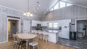A spacious kitchen with a central island, white cabinetry, and a large window providing natural light. - Crowfield (Edisto Island)