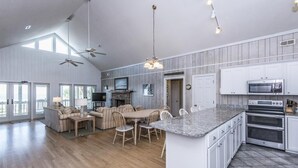 A spacious kitchen with a large island, wooden flooring, and modern appliances. - Crowfield (Edisto Island)