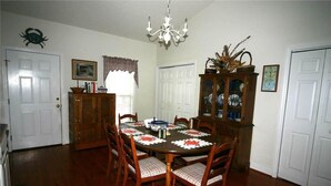 Una sala da pranzo con un tavolo in legno, sedie, un lampadario e una credenza con vetrate.