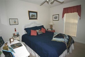 Une chambre à coucher avec un lit, une table de chevet, une lampe et une fenêtre avec des stores.