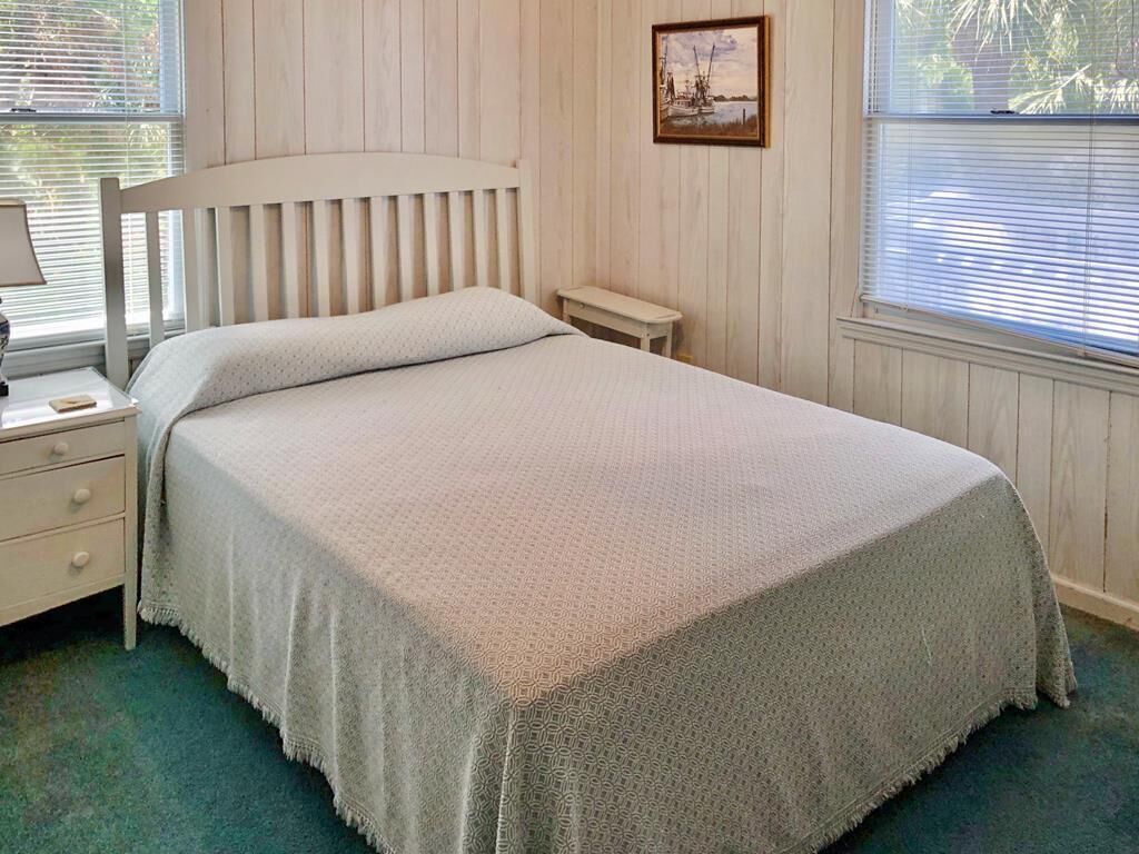 Un dormitorio con cabecera de madera, una mesita de noche y una ventana con persianas.