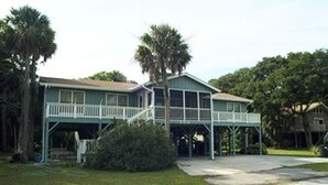 A two-story house with a balcony, surrounded by trees and a grassy yard. - Jumangi (Edisto Island)