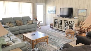 A living room with a sofa, armchairs, a coffee table, a TV, and a cabinet. - Jumangi (Edisto Island)