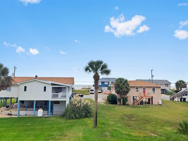 A coastal residential area with houses, a palm tree, and a clear sky.