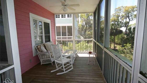 A porch with rocking chairs and a small table, overlooking a garden. - Pink Flamingo (Edisto Island)