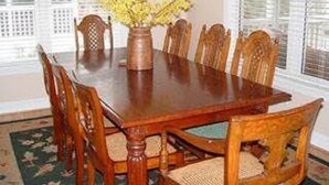 A dining table with six wooden chairs, a vase with yellow flowers, and a patterned rug. - Pink Flamingo (Edisto Island)