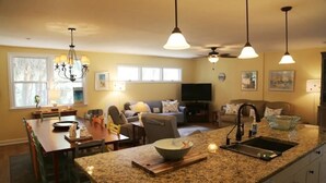 A kitchen with granite countertops, a dining area with chairs, a TV, and a ceiling fan. - Rooney Bin (Edisto Island)