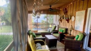 A cozy room with wicker furniture, a yellow chair, and a small table with a lamp. - Rooney Bin (Edisto Island)