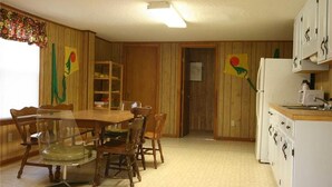 Une cuisine avec des meubles de rangement en bois, un réfrigérateur et une table à manger avec des chaises.