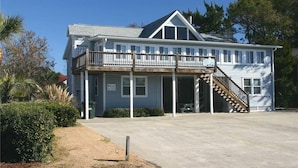 A two-story building with a balcony, a staircase, and a covered porch area.