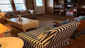 Ett mysigt vardagsrum med randiga soffor, ett soffbord, en bokhylla och en tv.