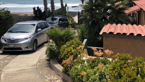 Een woongebied met uitzicht op de oceaan, geparkeerde auto's en palmbomen.