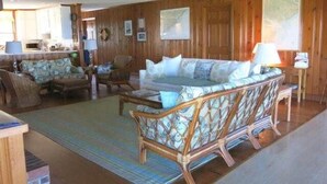 A spacious living room with a large sofa set, a dining table, and a wooden floor. - Top Gunn (Edisto Island)