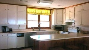 A kitchen with white cabinets, a wooden island, a microwave, and a sink. - Top Gunn (Edisto Island)