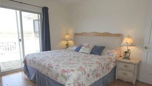 A bedroom with a bed, two bedside tables, and a sliding glass door leading to an outdoor area.