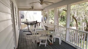 Une véranda abritée avec une table et des chaises, un hamac et un ventilateur de plafond.