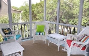 Relax in a serene garden setting with comfortable wicker furniture and lush greenery views.