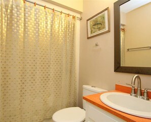 A bathroom with a toilet, sink, and shower curtain.