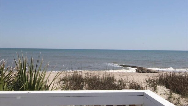 A beach view with a wooden deck and sparse vegetation. - Beach Retreat (Edisto Island)