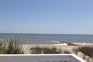 A beach view with a wooden deck and sparse vegetation. - Beach Retreat (Edisto Island)
