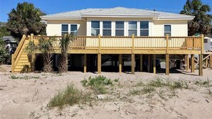 A two-story beach house with a wooden deck and a staircase leading to a covered area. - Beach Retreat (Edisto Island)
