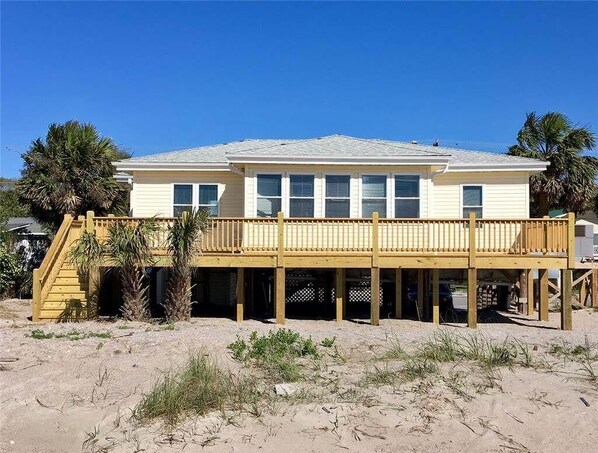 A two-story beach house with a wooden deck and a staircase leading to a covered area. - Beach Retreat (Edisto Island)