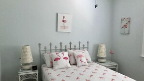 Ein Schlafzimmer mit einem Bett, zwei Nachttischen, einer Lampe auf jedem Nachttisch und einer Wand mit zwei gerahmten Bildern.