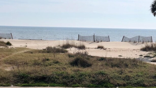 A beach with a fence and chairs along the shore. - Dowry (Edisto Island)