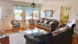 A cozy living room with a sofa, armchairs, a glass coffee table, and a dining table. - Dowry (Edisto Island)