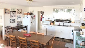 A compact kitchen with white cabinets, a wooden dining table, and a small island with a sink. - Dowry (Edisto Island)