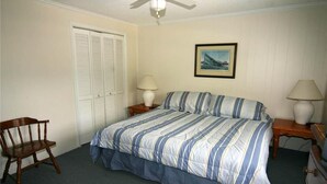 A bedroom with a bed, a chair, a nightstand, a lamp, a picture on the wall, and a closet. - Dreamcatcher (Edisto Island)