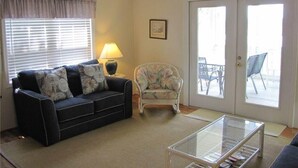 A living room with a sofa, armchair, glass coffee table, and a ceiling fan. - Dreamcatcher (Edisto Island)