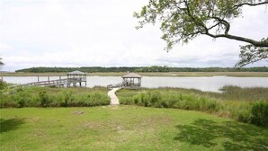 A gazebo by a lake with a wooden dock and a grassy area. - Dreamcatcher (Edisto Island)
