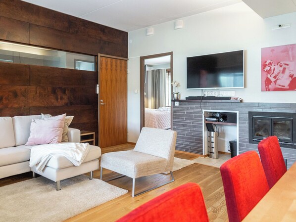 A modern living room with a sofa, armchair, and a dining area with a table and chairs.