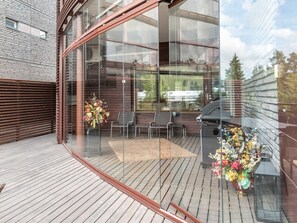 A modern outdoor deck with glass walls, wooden flooring, and outdoor furniture. - Tahko spa suites orange b 1 by Interhome (Nilsiä)