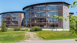 A modern building with a curved glass facade and a mix of wooden and metal materials.