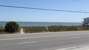 Una strada costiera con vista libera sull'oceano e una casa su palafitte sulla destra.