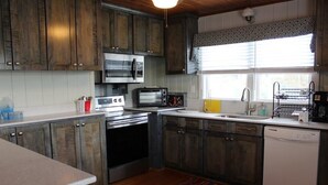 Una cucina con mobili in legno, un forno a microonde, un tostapane, un lavello e una lavastoviglie.