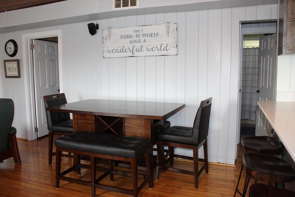A dining area with a wooden table and four chairs, a wall-mounted sign, and a door.