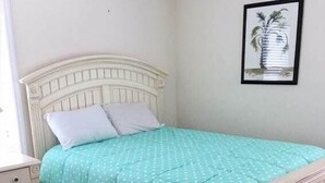 Un lit avec une tête de lit blanche et une couvre-lit turquoise à pois blancs.