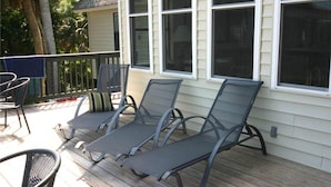 A covered outdoor area with two lounge chairs and a table, likely a patio or deck area. - Green Parrot (Edisto Island)