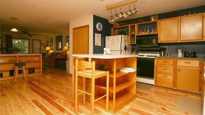 Une cuisine compacte avec des meubles en bois, un îlot central doté de tabourets, un réfrigérateur et une cuisinière.