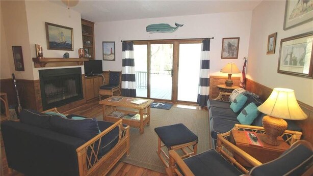 A cozy living room with a fireplace, a sofa, a coffee table, and a television. There is a sliding glass door leading to a balcony. - Miss Irene (Edisto Island)