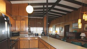 A kitchen with wooden cabinets, a large island, and pendant lighting. - Oristo (Edisto Island)