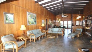 A spacious room with wicker furniture, tiled flooring, and wooden walls. - Oristo (Edisto Island)