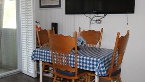 A dining area with a table set for four, wooden chairs, and a checkered tablecloth.